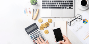 person calculating amount owing at their desk using phone and calculator