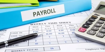 A picture of an employees hours worked chart with a blue payroll binder on top 