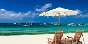 a beach chair and umbrella on a  sandy beach with blue water