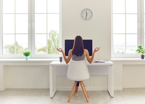 woman sitting at her desk making a zen mudra with her fingertips
